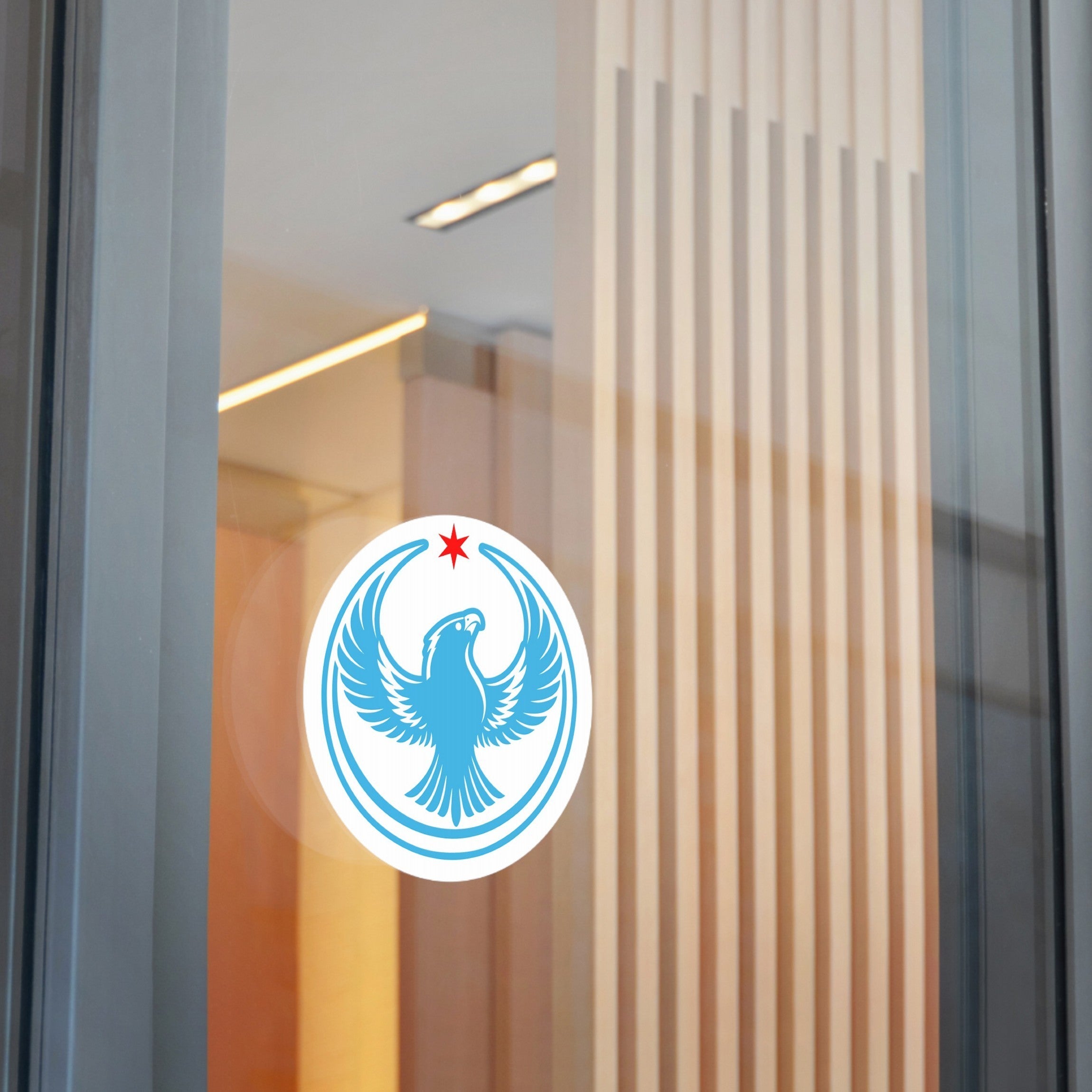Chicago Rebel Alliance Sticker featuring a stylized blue eagle with raised wings, encircled by rings and a red star above, affixed on a glass door with a softly lit interior.