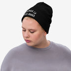 Person wearing a Chinga La Migra Hat, a black knit beanie with CHINGA LA PUTA MIGRA embroidered in white, conveying a bold anti-ICE message, suitable for activist gatherings and protest wear.