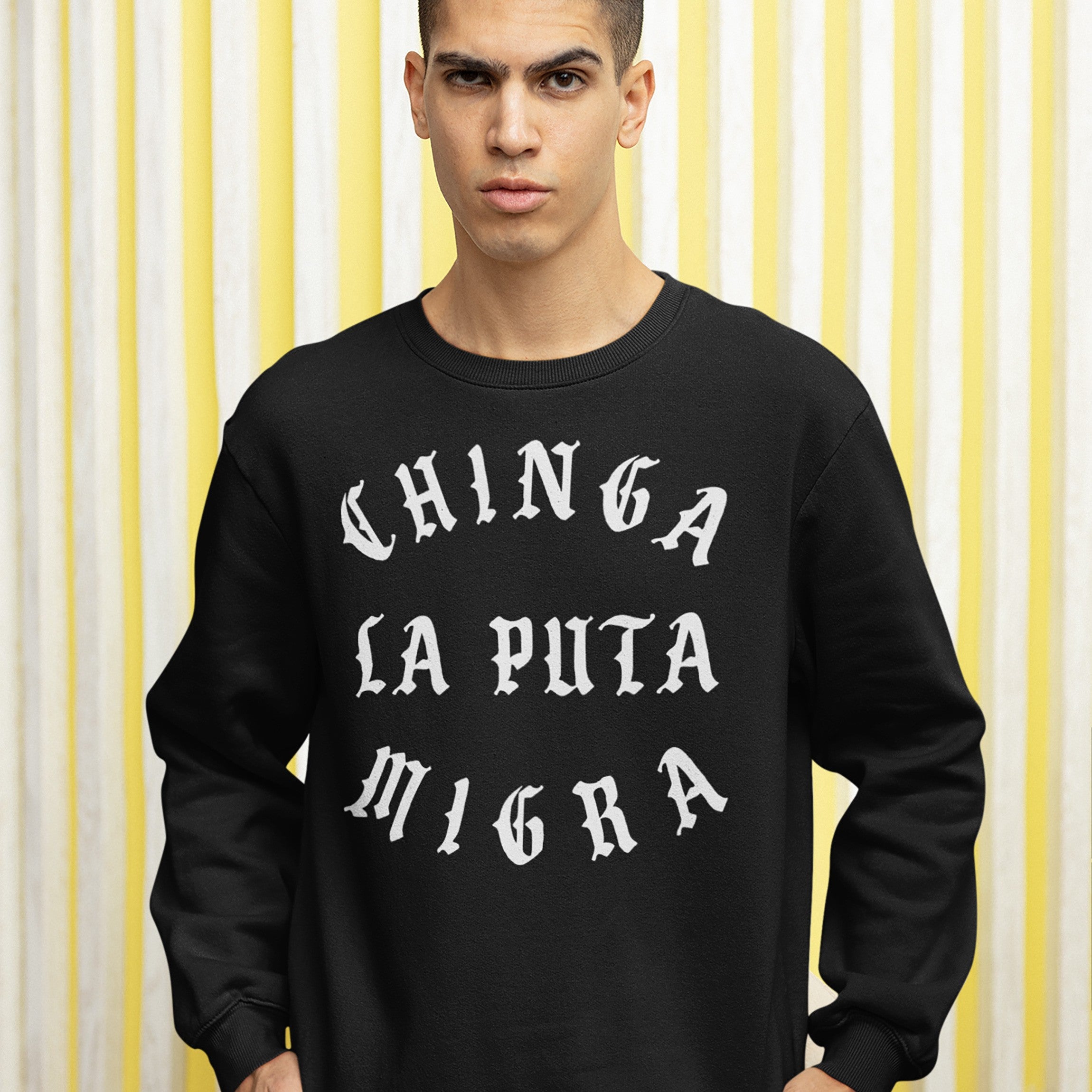 Young man in a black Chinga La Migra Hoodie & Sweatshirt with bold, white Old English text, protesting against CBP/ICE.