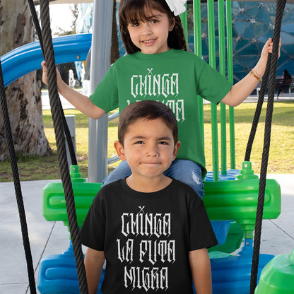 Two children wear Chinga La Migra T-shirts on a playground swing, showcasing bold gothic lettering that conveys a message of resistance and visibility against oppression.