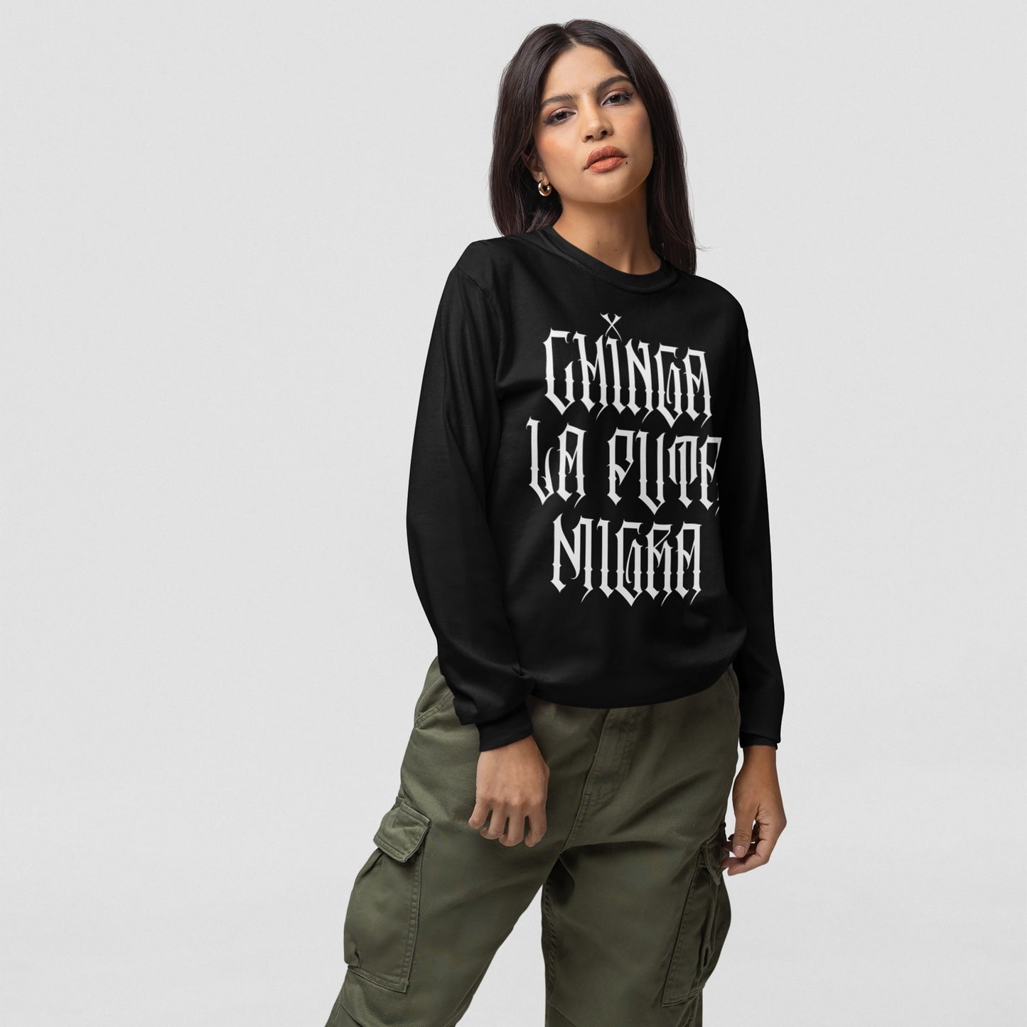 Model wearing the Chinga La Migra T-shirt with bold Chinga La Puta Migra text in gothic font, paired with olive cargo pants, embodying resistance and conviction through fashion.