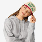 Young woman models the Chinga Tu MAGA Hat, featuring beige front, red brim, and bold green lettering. This anti-fascist design symbolizes resistance, aligning with values of equality and anti-racism.