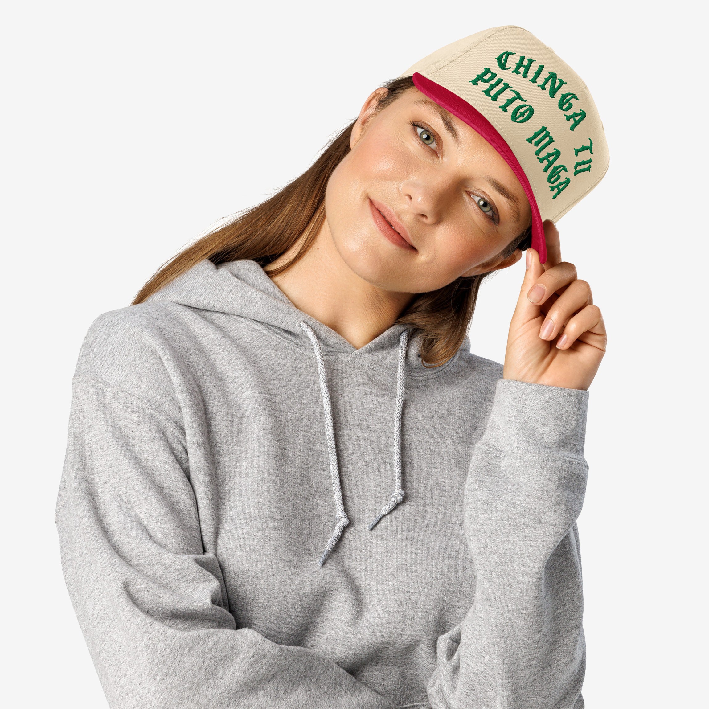 Young woman models the Chinga Tu MAGA Hat, featuring beige front, red brim, and bold green lettering. This anti-fascist design symbolizes resistance, aligning with values of equality and anti-racism.