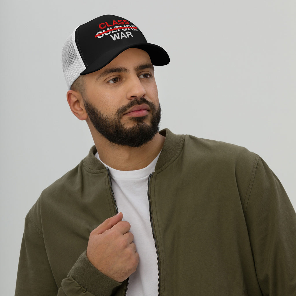 Young man wearing the Class War Hat, featuring a black front with CULTURE crossed out. CLASS in red and WAR in white are displayed, symbolizing focus on economic justice and solidarity.