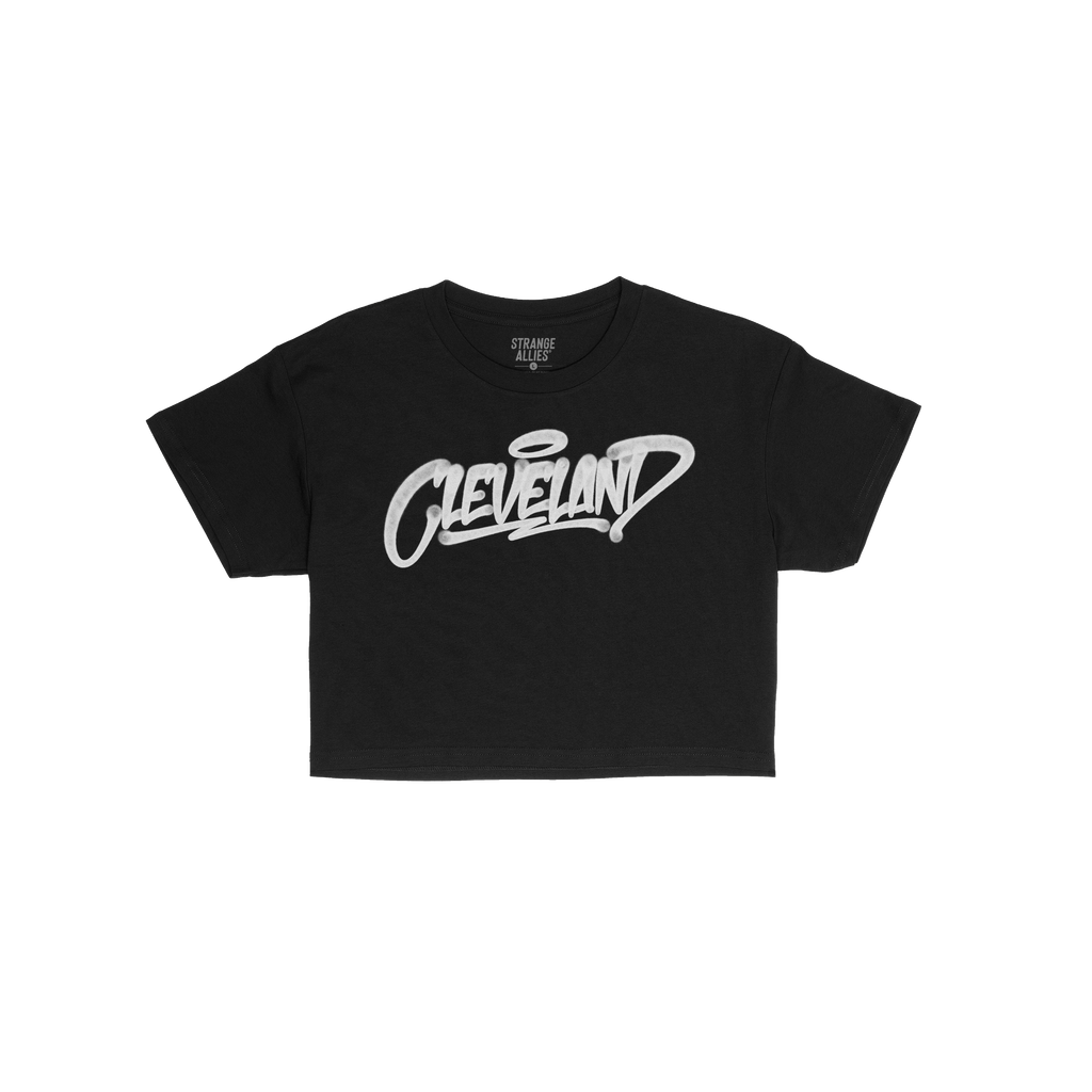 Cleveland Handstyle Women's Baby Tee featuring graffiti-style Cleveland text with a halo, laid flat. This black short-sleeve 