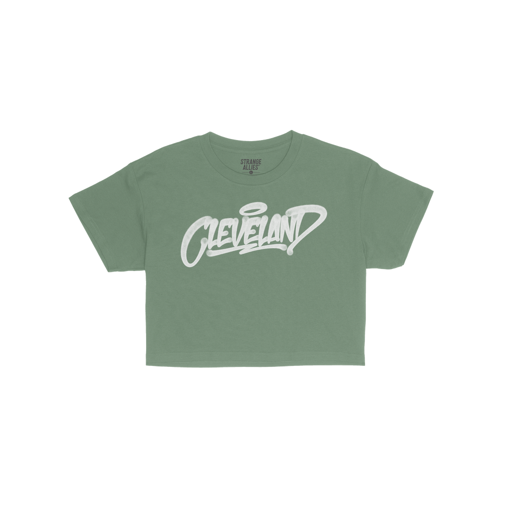 Cleveland Handstyle Women's Baby Tee features a green short-sleeve design with “Cleveland” in white graffiti script on th