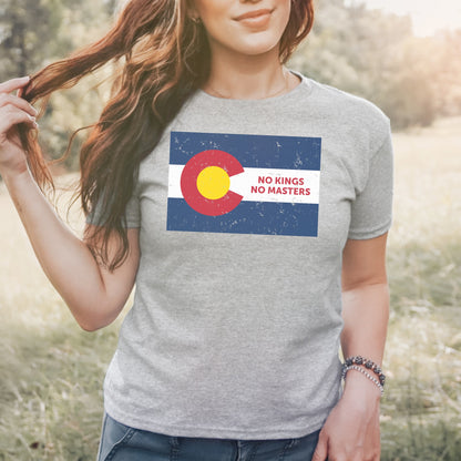 Person wears the Colorado No Kings Flag Women's Baby Tee, featuring a distressed state flag design with bold NO KINGS NO MASTERS text, embodying defiance and resistance against authoritarianism.