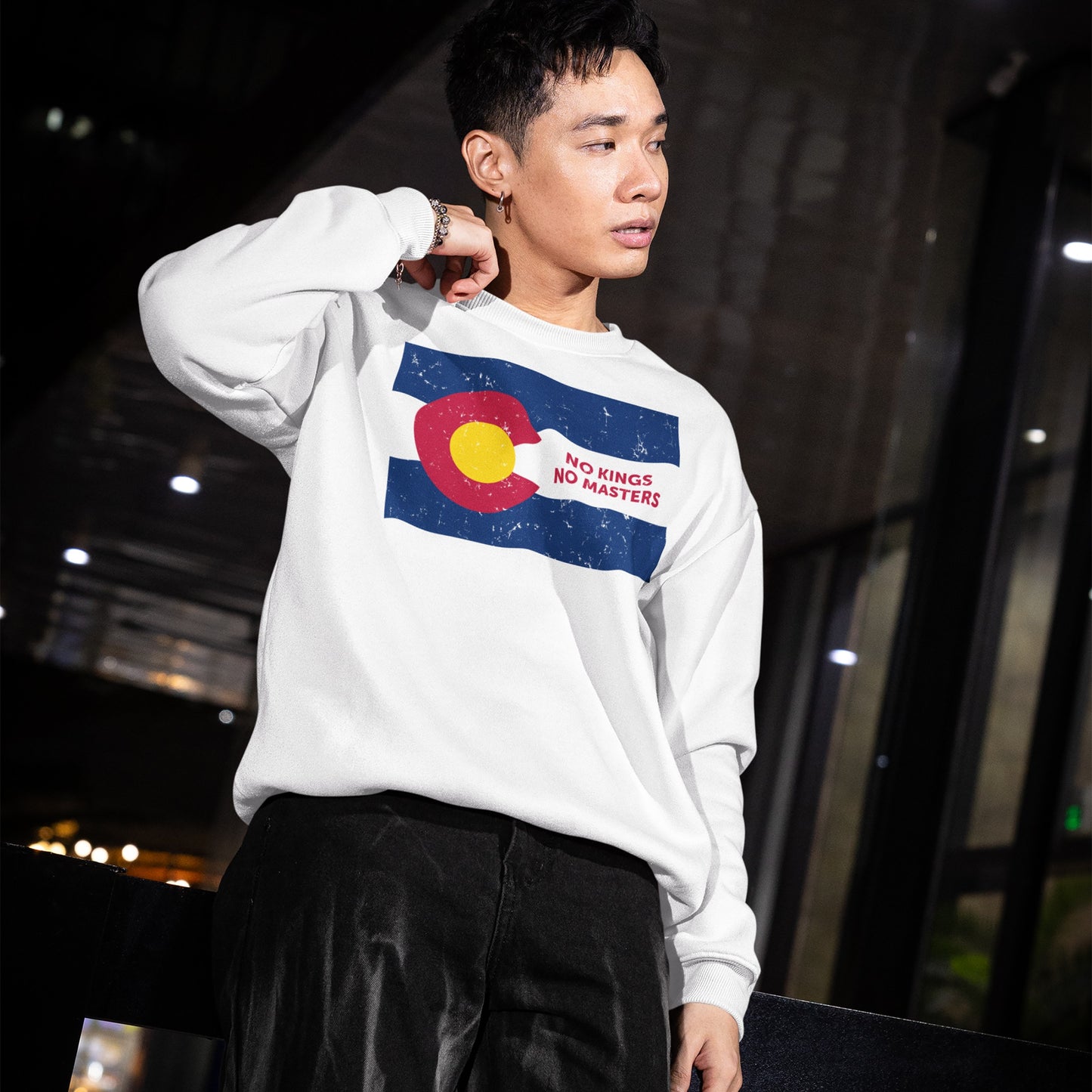 A young man models the Colorado No Kings Flag Hoodie & Sweatshirt, featuring a stylized Colorado flag with NO KINGS NO MASTERS, embodying a message of independence and defiance.