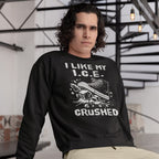 Crushed ICE Hoodie & Sweatshirt: Young man in a black sweatshirt featuring a sneaker crushing ice cubes, expressing an anti-ICE message in a modern setting with spiral staircase and exposed-bulb lights.