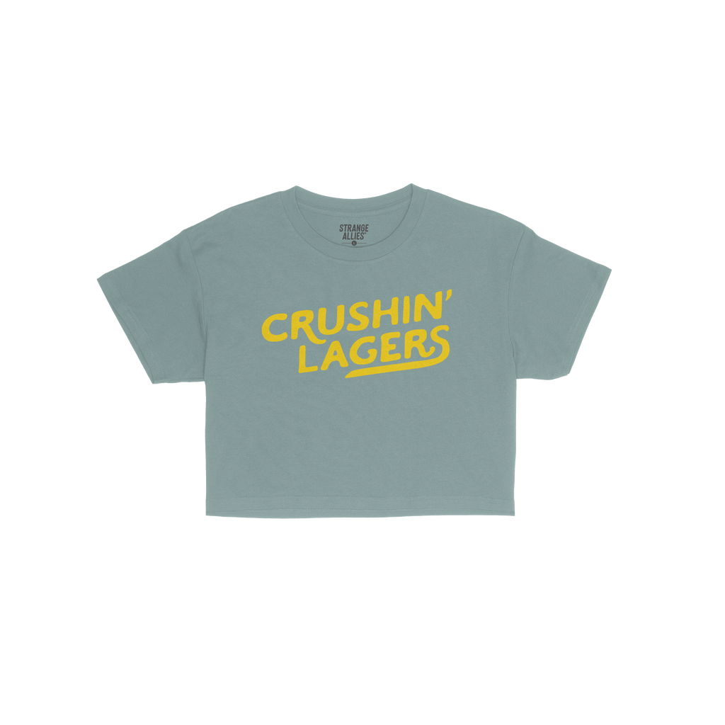 Crushin' Lagers Women's Baby Tee features bold, yellow “CRUSHIN’ LAGERS” text on a navy blue, cropped tee. Perfect for 
