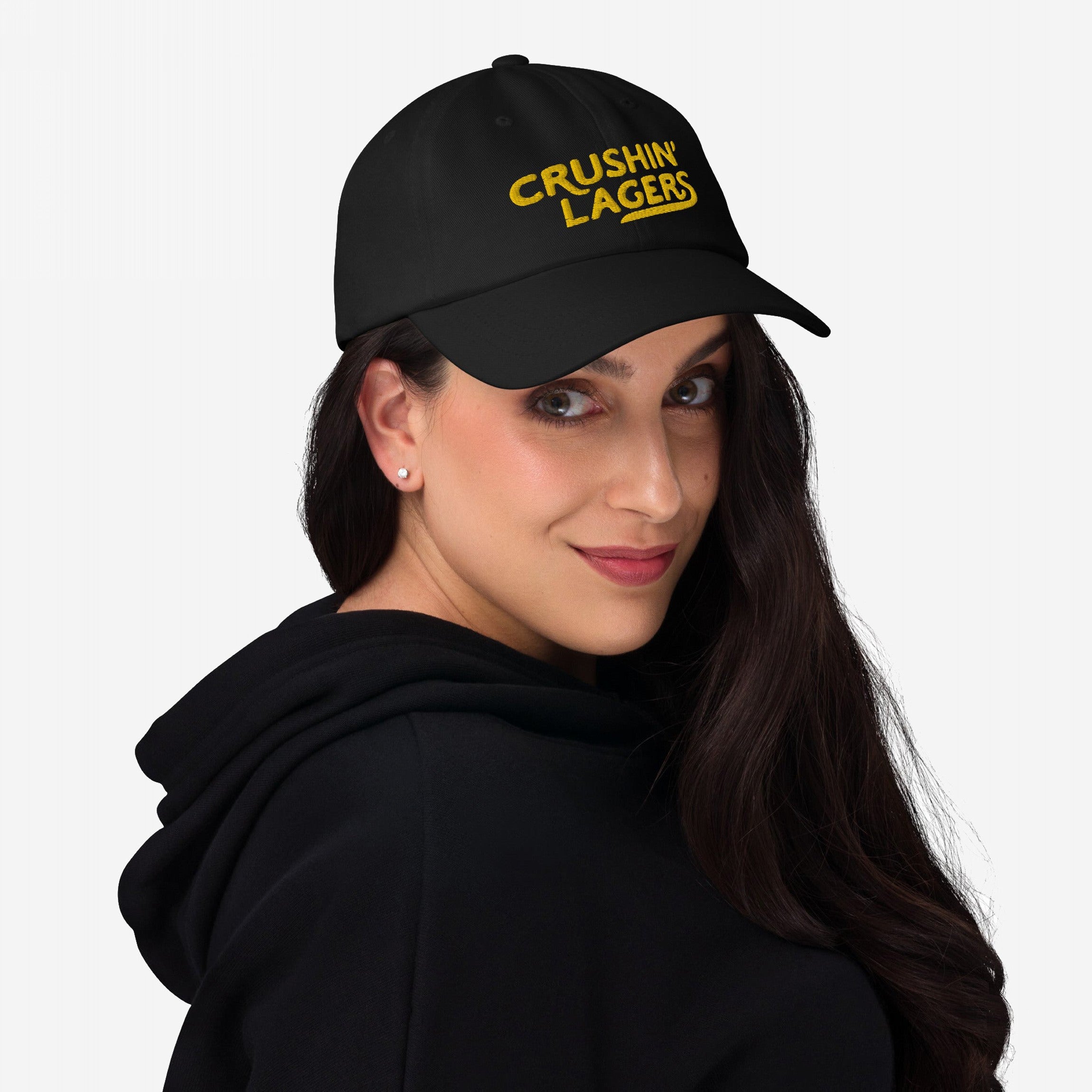 Young woman models the Crushin' Lagers Hat, a black baseball cap with yellow CRUSHIN' LAGERS embroidery, embodying retro style and lager loyalty, perfect for casual brewery visits or relaxed gatherings.