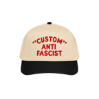 Two-tone cap with a beige crown and black bill, featuring bold red embroidery, CUSTOM ANTI FASCIST, showcasing the Custom Ant