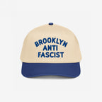 Custom Anti-Fascist 5-Panel Hat with a beige crown and navy brim features bold blue BROOKLYN ANTI FASCIST embroidery, offering a stylish, structured design perfect for activism and personalization.