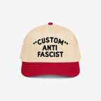 Custom Anti-Fascist 5-Panel Hat with beige crown and red bill, featuring bold black CUSTOM ANTI FASCIST embroidery, symbolizing activism and individuality. Adjustable snapback for comfort.