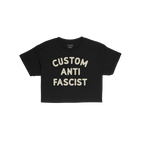 Custom Anti-Fascist Women's Baby Tee featuring chunky off-white lettering, laid flat. This short-sleeved black T-shirt embodi