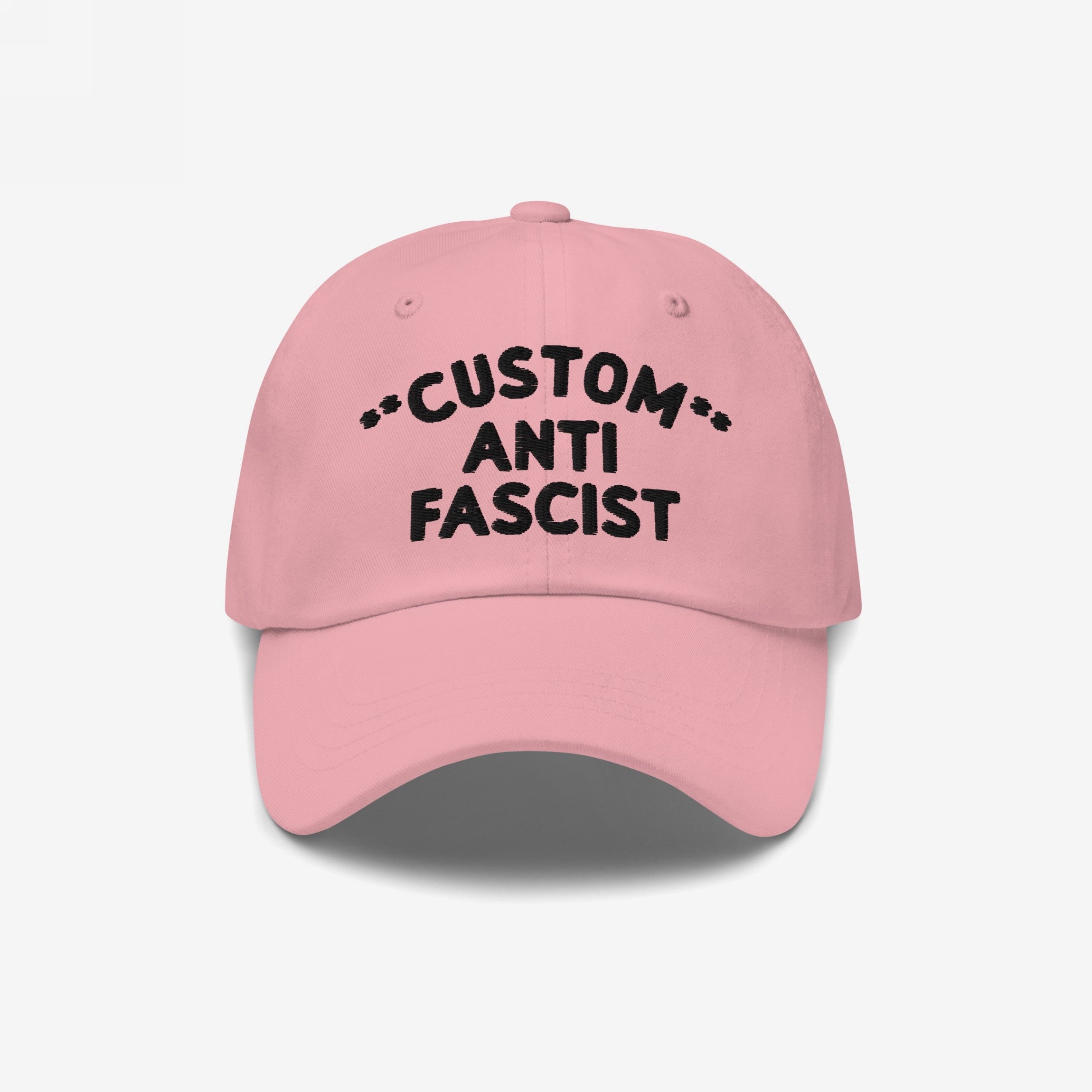 Pink Custom Anti-Fascist Dad Hat with black CUSTOM ANTI FASCIST embroidery, showcasing a bold statement in a relaxed, six-panel design with adjustable strap and pre-curved visor.