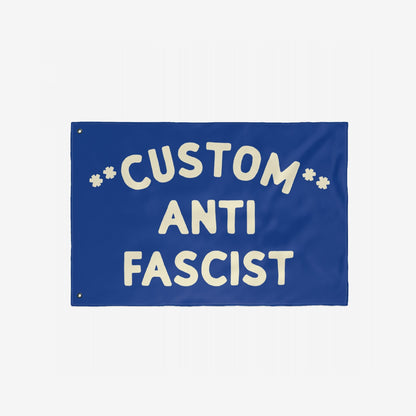 Custom Anti-Fascist Flag featuring bold off-white text on a solid blue background with grommets for hanging. Fully customizable header text, ideal for displaying anti-fascist messages at events or home.