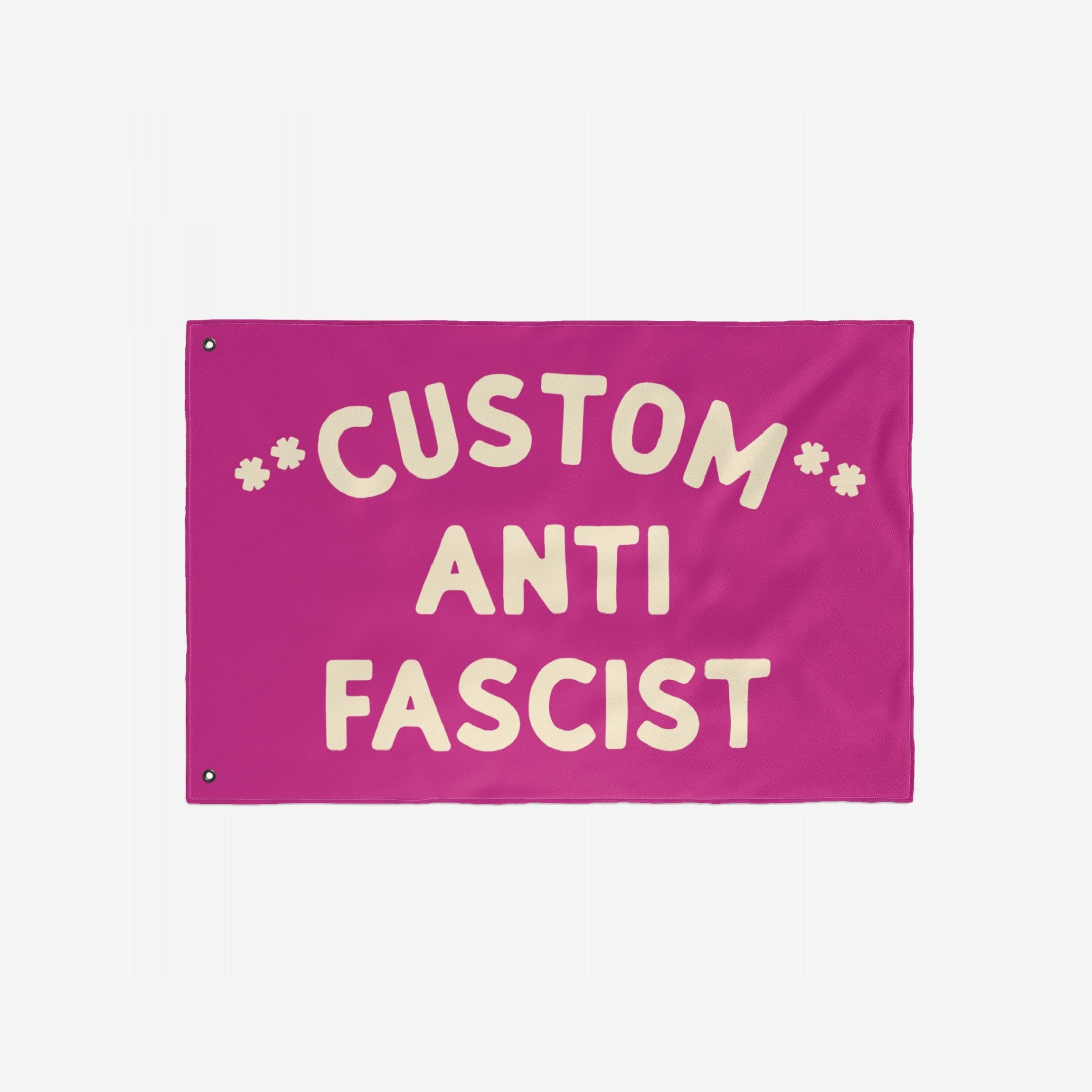 Custom Anti-Fascist Flag featuring bold cream letters on a magenta-pink background with grommets for hanging. Personalize with your message to promote equality and stand against fascism.