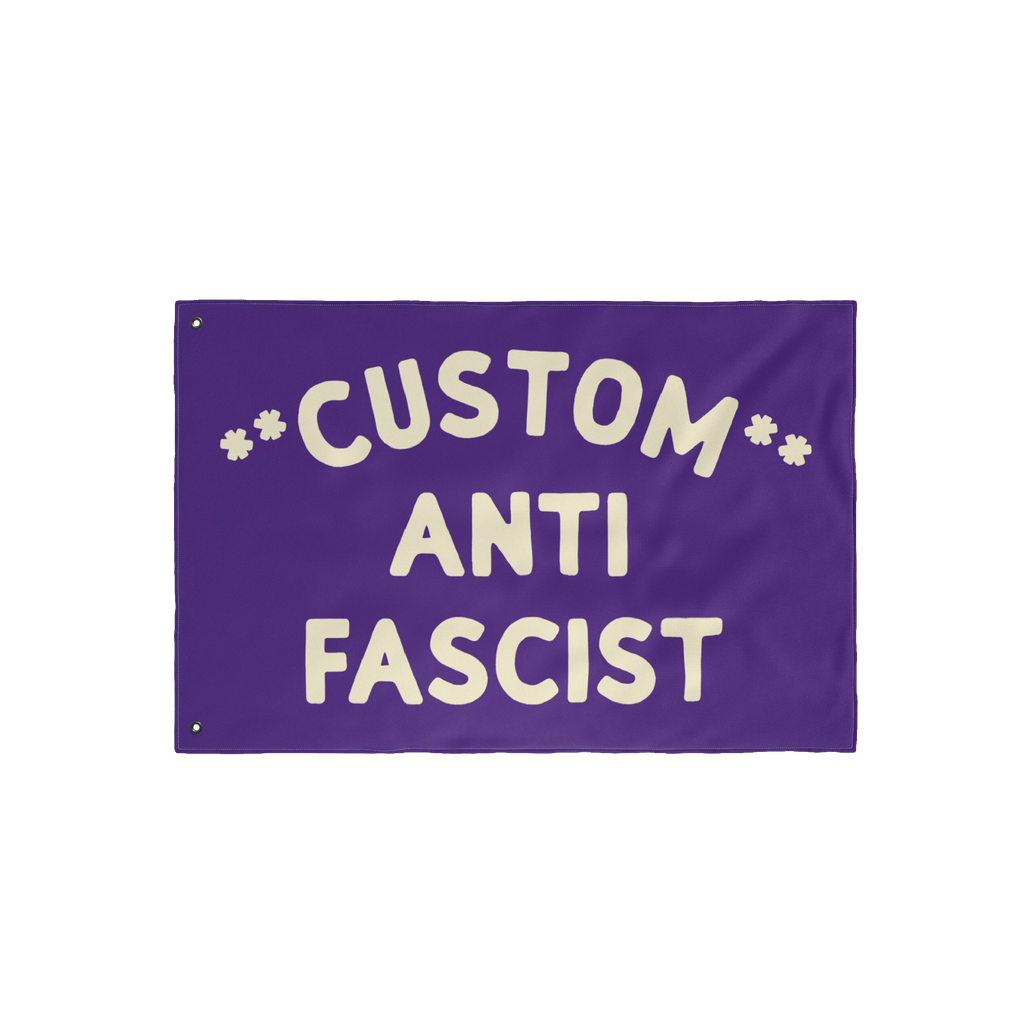 Custom Anti-Fascist Flag with hand-lettered text CUSTOM ANTI FASCIST and star-like asterisks. Features two grommets for hangi