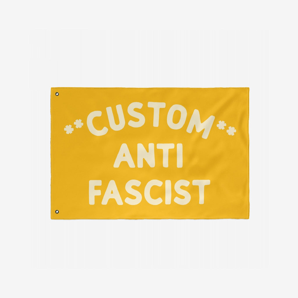 Custom Anti-Fascist Flag featuring bold off-white text on a yellow background, with two metal grommets for hanging. Ideal for promoting unity and resistance at events or home displays.