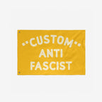 Custom Anti-Fascist Flag featuring bold off-white text on a yellow background, with two metal grommets for hanging. Ideal for promoting unity and resistance at events or home displays.
