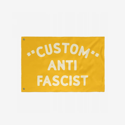 Custom Anti-Fascist Flag featuring bold off-white text on a yellow background, with two metal grommets for hanging. Ideal for promoting unity and resistance at events or home displays.