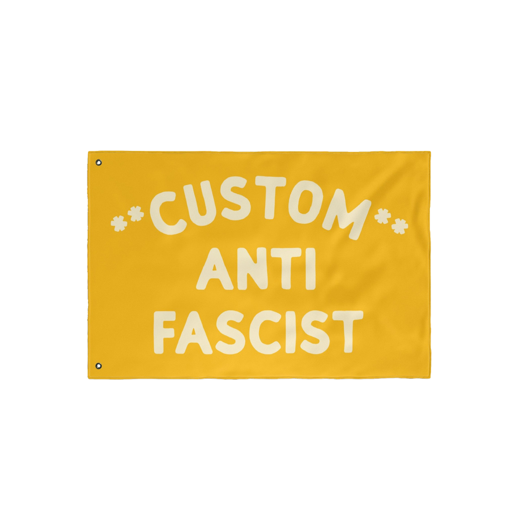 Custom Anti-Fascist Flag featuring bold off-white text on a yellow background, with two metal grommets for hanging. Ideal for