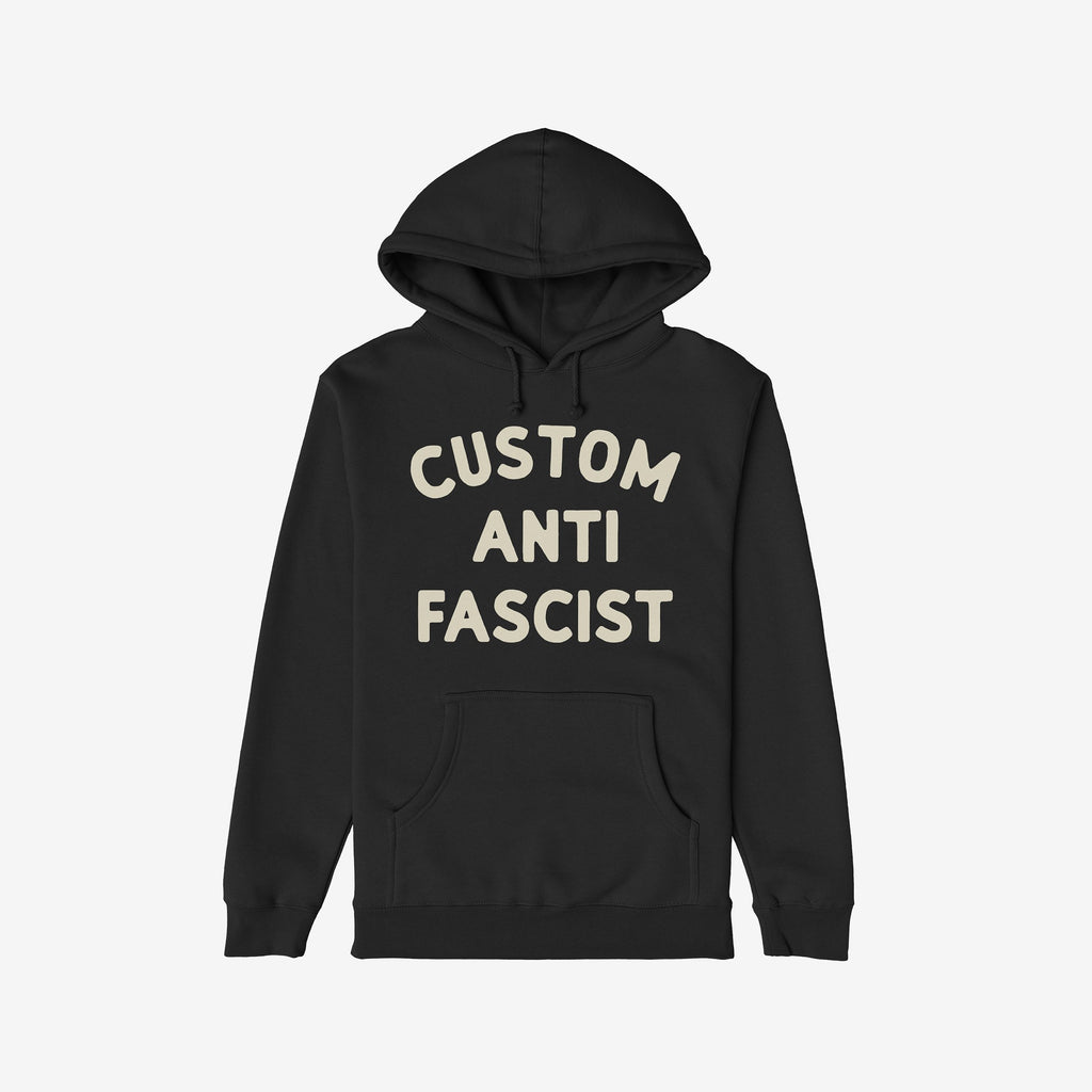 The Custom Anti-Fascist Hoodie features bold off-white text, CUSTOM ANTI FASCIST, on a black pullover with a kangaroo pocket and drawstring hood, embodying activism and comfort.