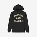 The Custom Anti-Fascist Hoodie features bold off-white text, CUSTOM ANTI FASCIST, on a black pullover with a kangaroo pocket and drawstring hood, embodying activism and comfort.