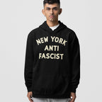 Custom Anti-Fascist Hoodie: A young person models a black hoodie with NEW YORK ANTI FASCIST text in cream, featuring a kangaroo pocket, perfect for making a bold, activist statement.