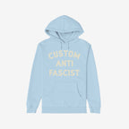 Custom Anti-Fascist Hoodie with front kangaroo pocket features CUSTOM ANTI FASCIST in cream. Ideal for activists, this light-blue pullover is designed for warmth and statement-making.