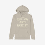 Custom Anti-Fascist Hoodie with Custom Anti Fascist in cream block letters. Features a kangaroo pocket and drawstrings, ideal for making a statement while staying warm. Personalize with your own empowering message.