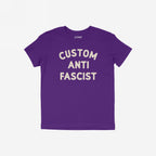 Custom Anti-Fascist Kids T-shirt featuring bold off-white block letters, laid flat. Personalize the Custom part to reflect meaningful words, promoting activism and empowerment for young voices in durable, comfortable fabric.