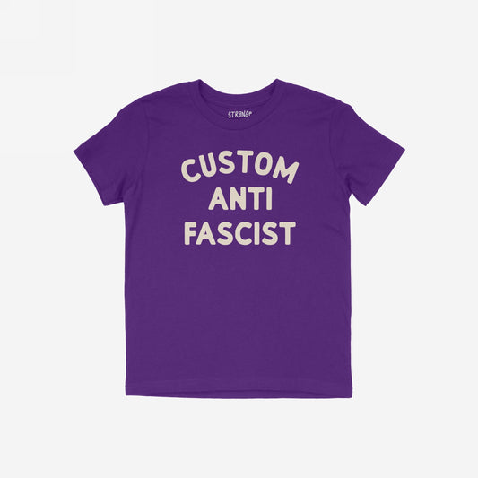 Custom Anti-Fascist Kids T-shirt featuring bold off-white block letters, laid flat. Personalize the Custom part to reflect meaningful words, promoting activism and empowerment for young voices in durable, comfortable fabric.