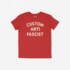 Custom Anti-Fascist Kids T-shirt featuring bold, off-white CUSTOM ANTI FASCIST text on a red short-sleeve. Ideal for young activists, this tee combines comfort with a powerful message.