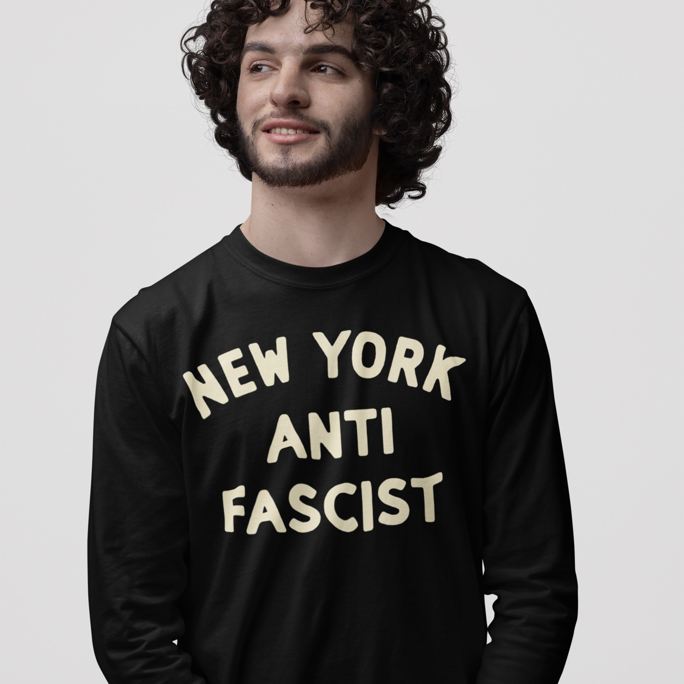 Custom Anti-Fascist Long Sleeve T-shirt featuring NEW YORK ANTI FASCIST slogan in off-white letters, worn by a young man. Ideal for cooler days and activism, expresses bold, personalized statements.