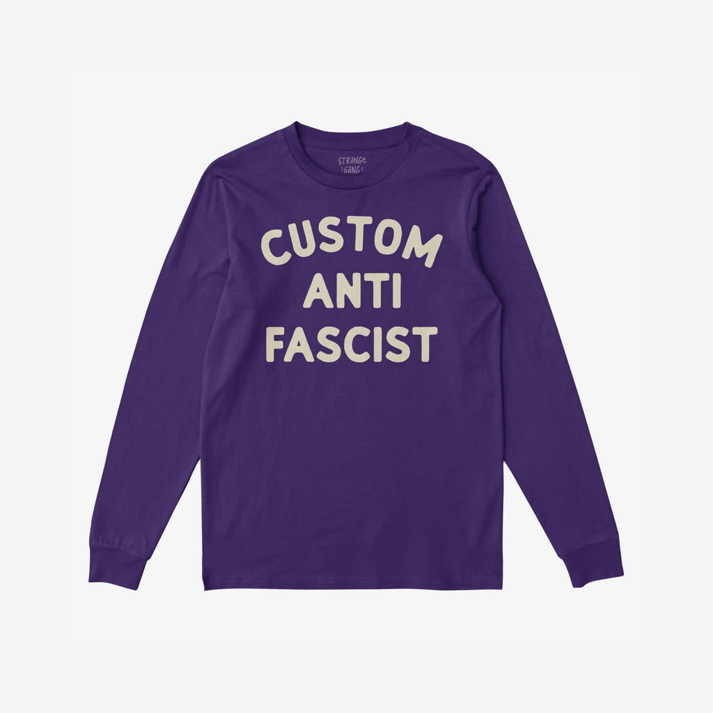 Custom Anti-Fascist Long Sleeve T-shirt featuring CUSTOM ANTI FASCIST in off-white block letters on deep purple, ideal for activism and expression. Personalize with your city or message.