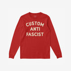 Custom Anti-Fascist Long Sleeve T-shirt laid flat, featuring bold cream text CUSTOM ANTI FASCIST on soft red fabric, inviting personalization for activism and expression.