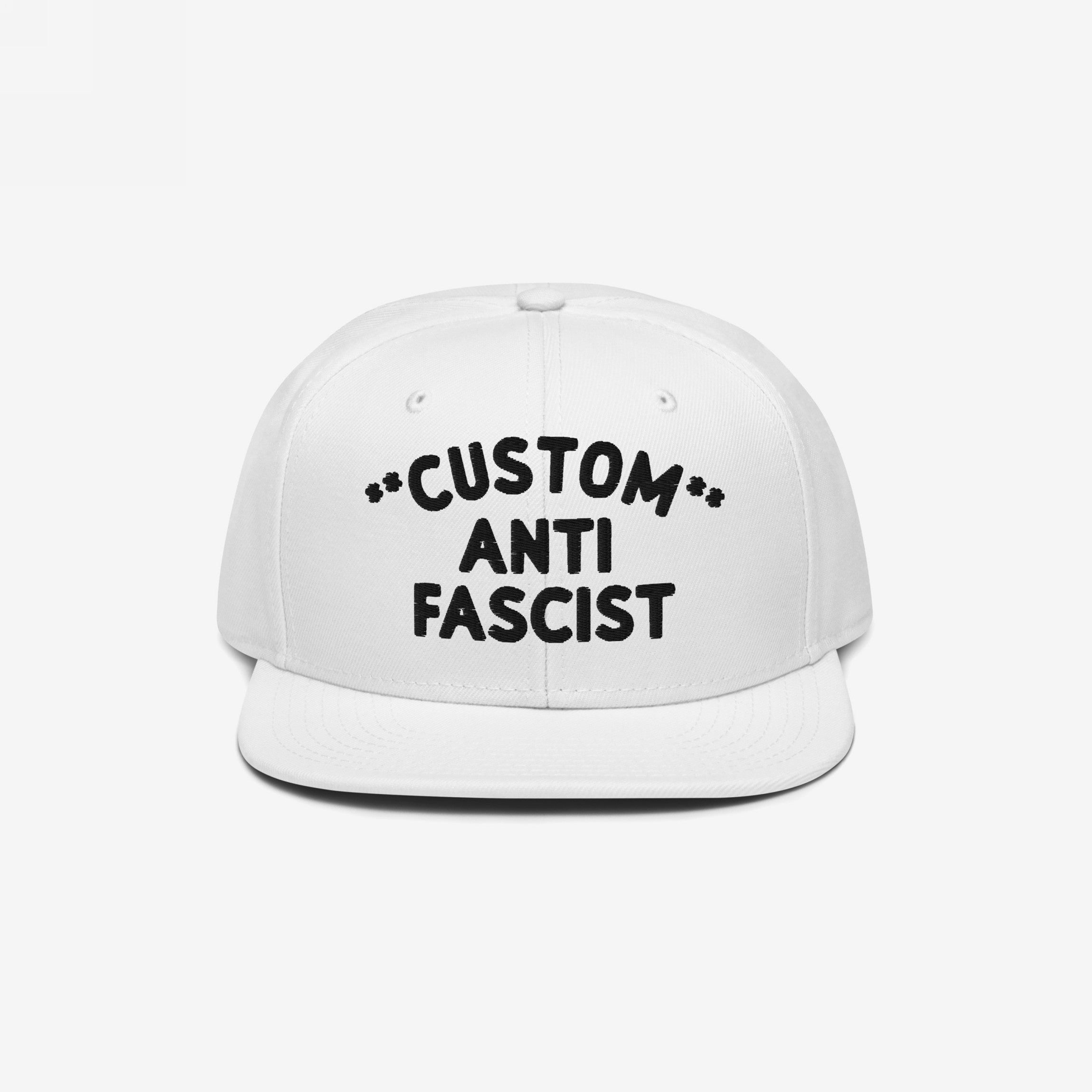 Custom Anti-Fascist Snapback Hat featuring bold black embroidery on a white cap, highlighting an anti-fascist message. Personalizable text option with adjustable snapback closure for comfort and style.