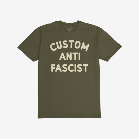 Custom Anti-Fascist T-shirt displaying CUSTOM ANTI FASCIST in large block letters on the chest, showcasing a powerful statement in off-white against an olive-green backdrop.