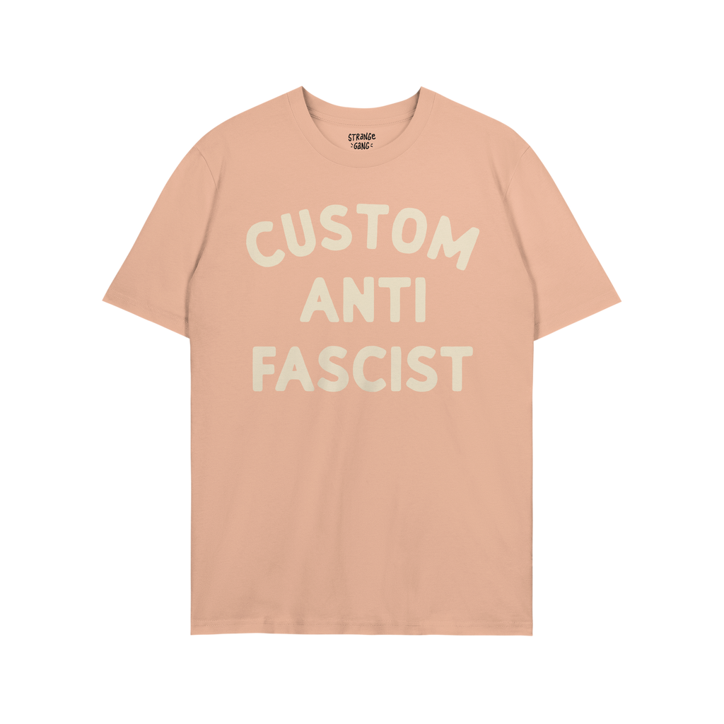 Light blue Custom Anti-Fascist T-shirt with cream block letters reading “CUSTOM ANTI FASCIST” across the front, embodying