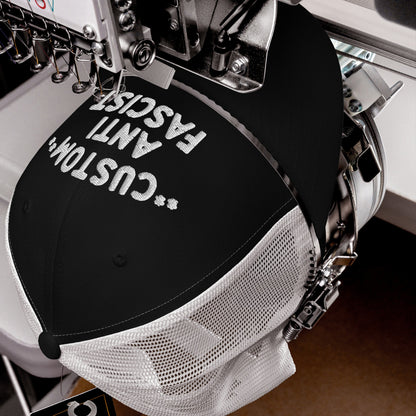 Custom Anti-Fascist Trucker Hat in embroidery machine, stitching white thread on black front panel with white mesh back. Personalize your message, showcasing bold anti-fascist stance with breathable design.