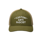 Custom Anti-Fascist Trucker Hat featuring an olive green front and tan mesh back. Embroidered CUSTOM ANTI FASCIST text, adjus