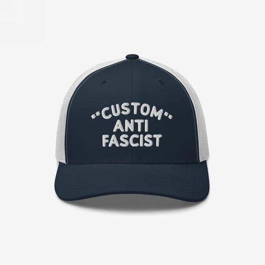 Custom Anti-Fascist Trucker Hat with navy front and white mesh back, featuring bold white embroidery. Offers adjustable fit and customizable city/message in selected colors, symbolizing equality and anti-fascist pride.