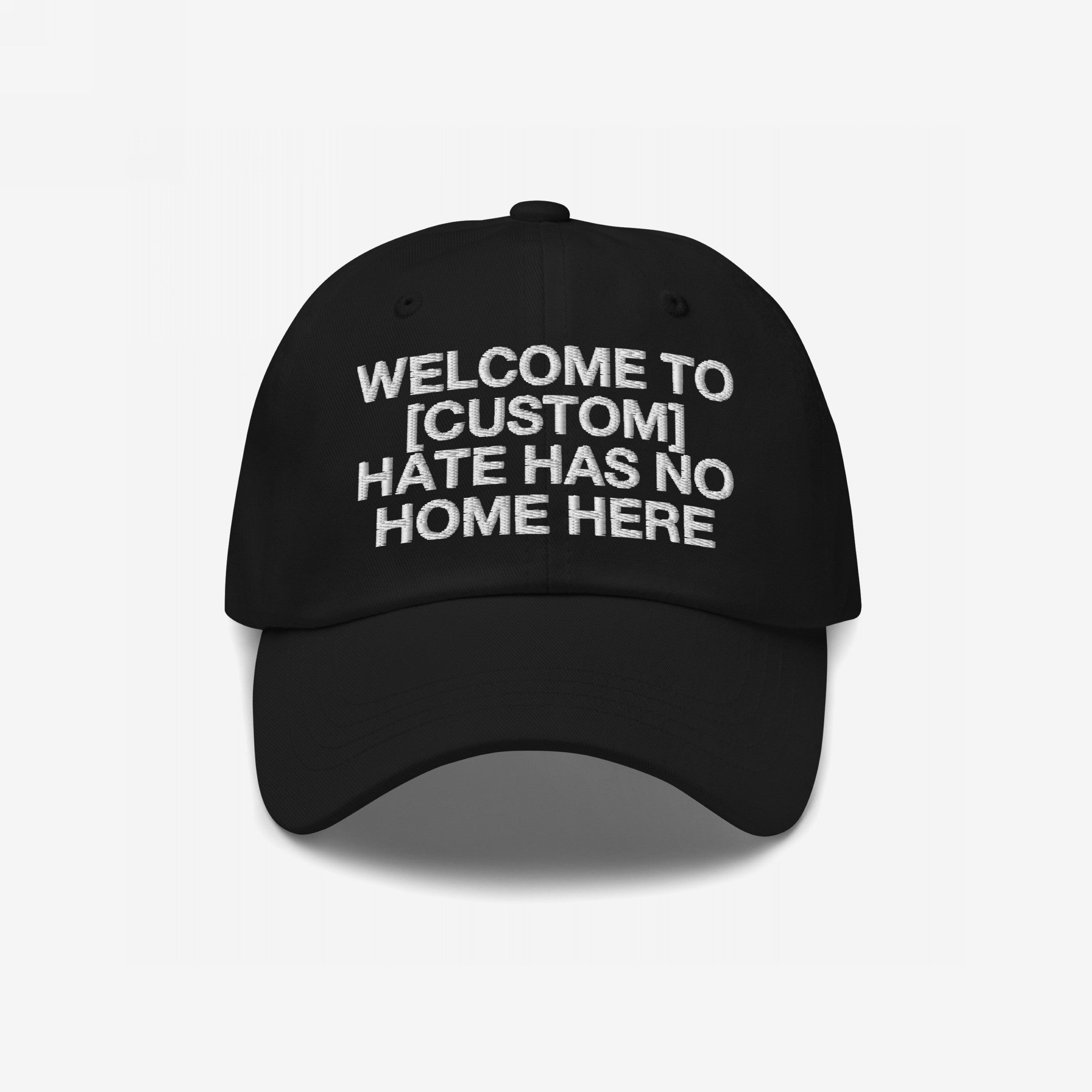 Custom Hate Has No Home Here Dad Hat features a black cap with white embroidered text promoting inclusion. Personalize with your city name. Adjustable strap and curved brim for comfort and style.