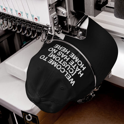 Close-up of the Custom Hate Has No Home Here Dad Hat being embroidered on a machine, showcasing the impactful message and craftsmanship that align with promoting equality and inclusion.