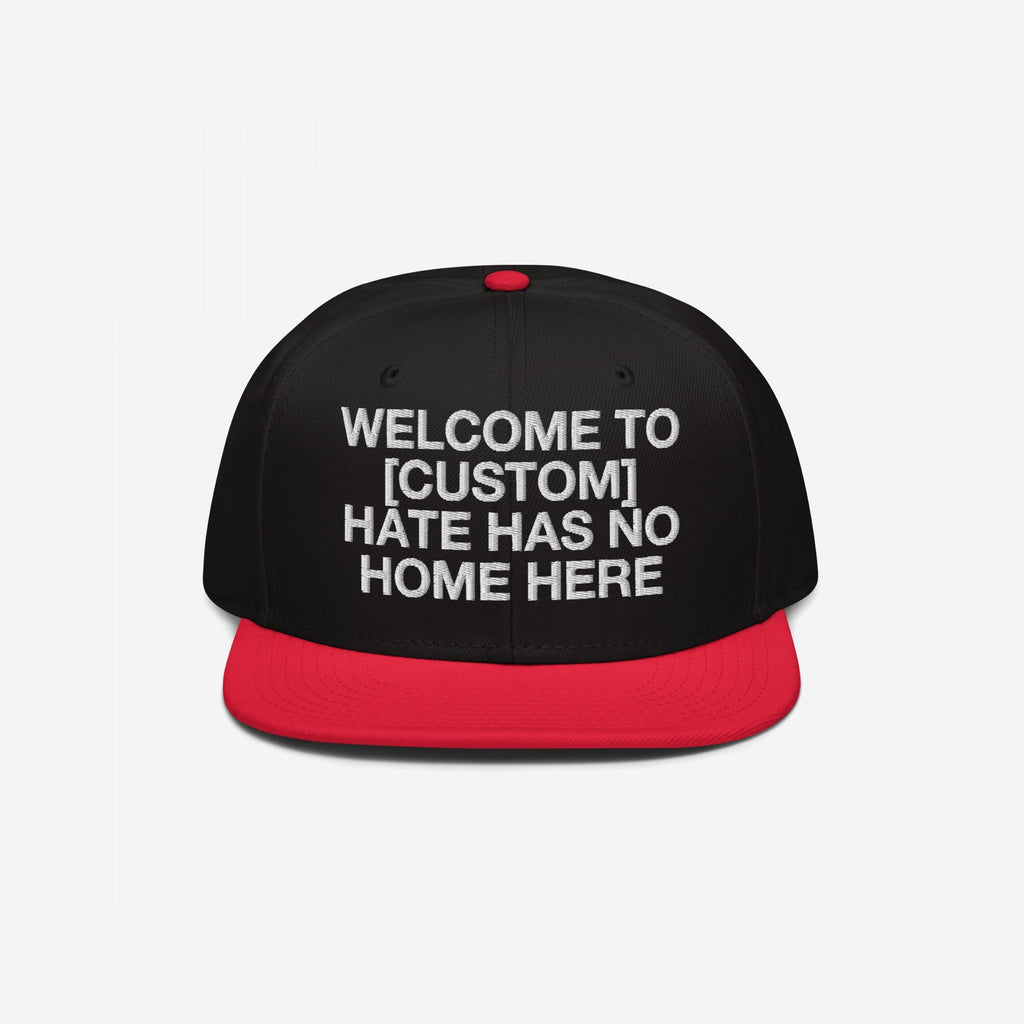 Custom Hate Has No Home Here Snapback Hat features a bold, white embroidered message promoting unity and justice, set against a structured black crown with a contrasting red flat brim and adjustable snap closure.