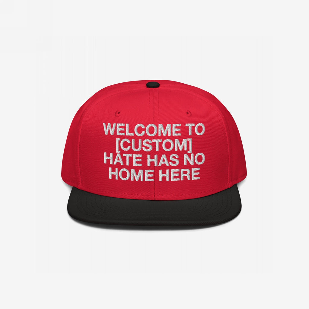 Custom Hate Has No Home Here Snapback Hat with a red crown, black flat brim, and embroidered front message promoting unity and anti-hate values. Features adjustable snap closure and EGOPROOF logo on the back.