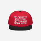 Custom Hate Has No Home Here Snapback Hat with a red crown, black flat brim, and embroidered front message promoting unity and anti-hate values. Features adjustable snap closure and EGOPROOF logo on the back.