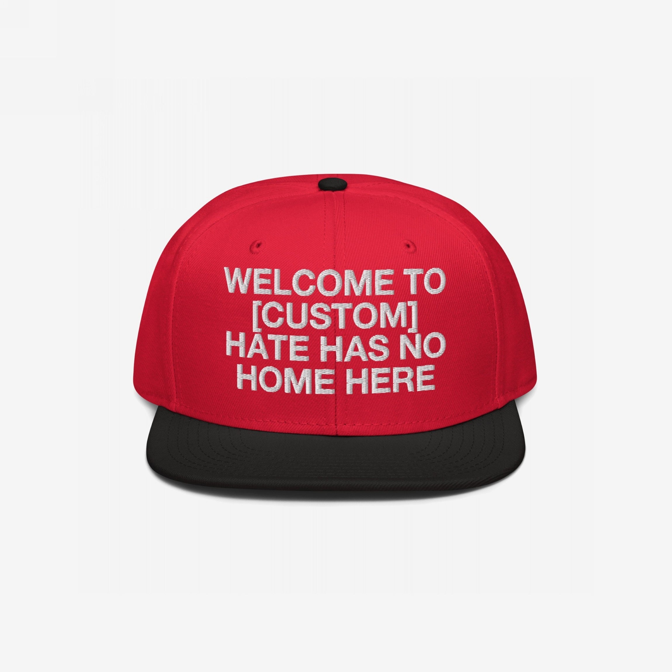 Custom Hate Has No Home Here Snapback Hat with a red crown, black flat brim, and embroidered front message promoting unity and anti-hate values. Features adjustable snap closure and EGOPROOF logo on the back.
